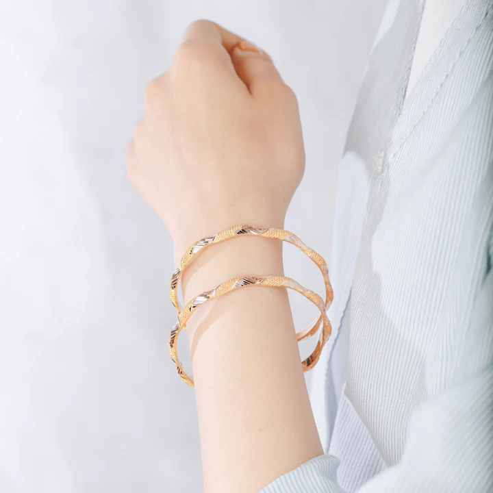 A wrist stacked with fine gold bracelets